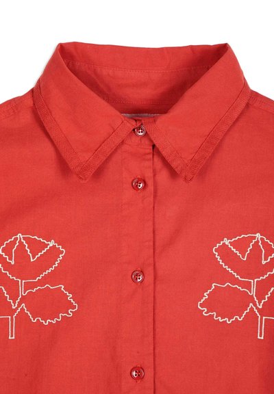 Chemise rouge à boutons avec col pointu et motifs de feuilles blanches brodés de chaque côté de la poitrine.