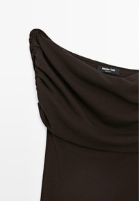 Zwarte off-shoulder jurk met geplooide details aan één zijde, voorzien van een brede gedrapeerde halslijn en Massimo Dutti-label aan de binnenkant van de kraag.