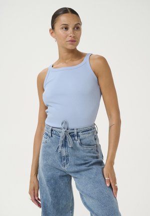 Helles blaues Rippen-Top mit quadratischem Ausschnitt, kombiniert mit hochtaillierten hellen Jeans aus Denim, die mit einem Bindegürtel detailiert sind.
