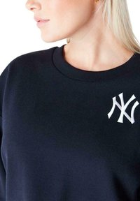 Felpa navy con collo rotondo e polsini a coste, decorata con il logo "NY" ricamato in bianco sul petto. Tessuto morbido.