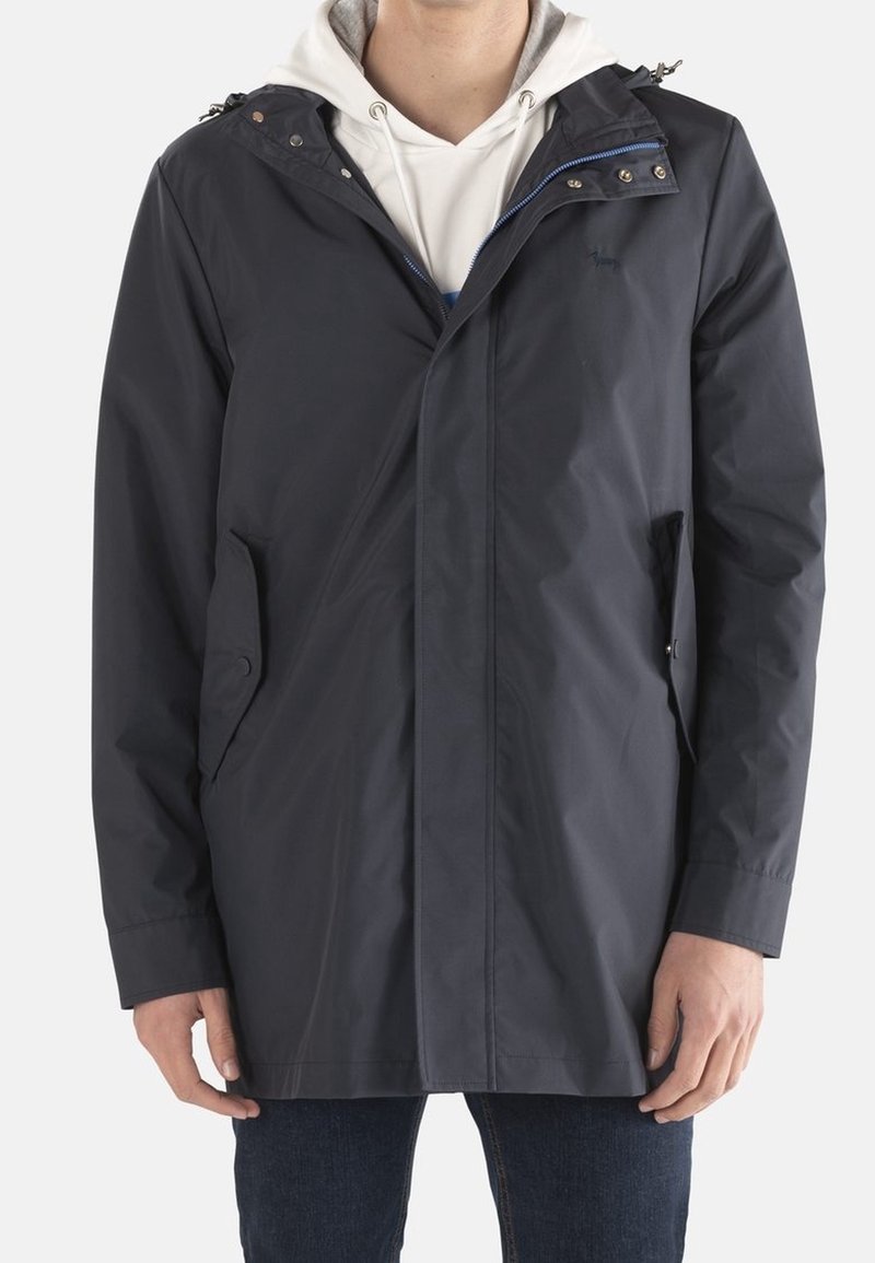 Dunkelblauer wasserdichter Herrenmantel mit Kapuze, Reißverschluss und Druckknöpfen, zwei seitlichen Taschen und glatter Textur. Über einem Hoodie getragen.