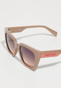 Square sunglasses with a light beige plastic frame, gradient brown lenses, and a pink accent on the arm with 'LIU JO' logo detail.