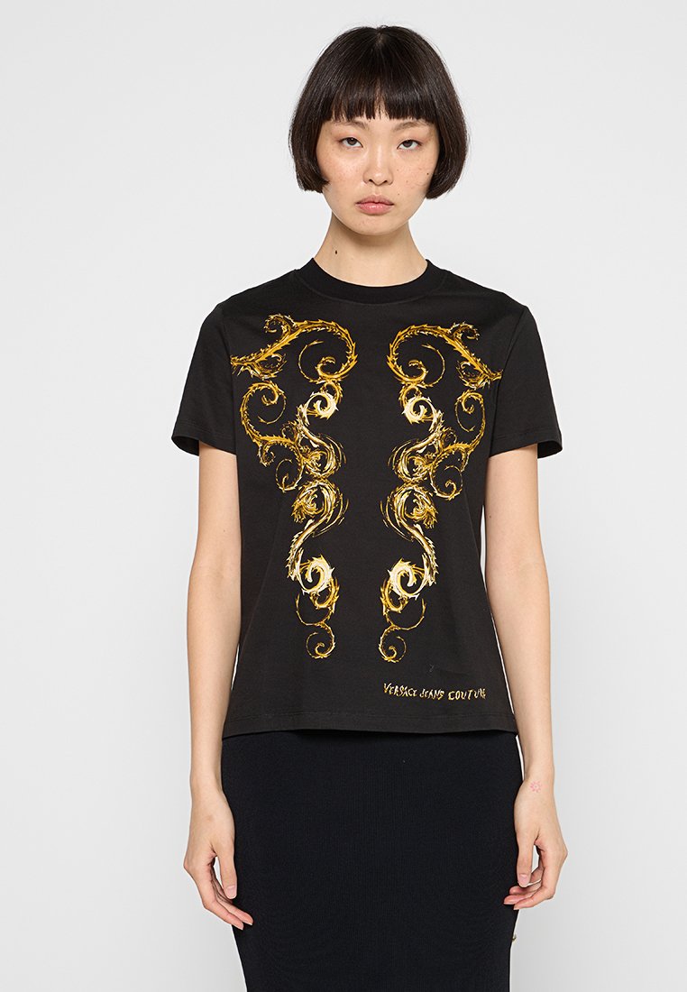 T-shirt noir avec des motifs dorés tourbillonnants sur le devant, à manches courtes et à col rond. Fabriqué en tissu lisse.