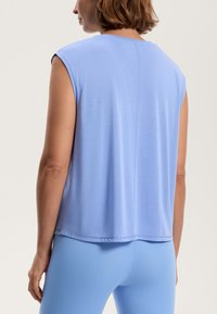Světle modrý bezramínkový top vyrobený z měkkého materiálu, se uvolněným střihem a hladkým povrchem. Jednoduchý design s detailem zadního švu.