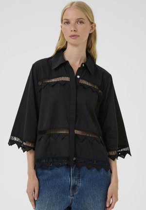 Maglietta nera con colletto e ritagli orizzontali trasparenti, maniche ampie e design con orlo a scallop. Realizzata in tessuto leggero, vestibilità comoda.