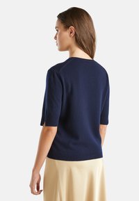 Granatowy sweter z krótkim rękawem, dzianinowy, z ribbami na mankietach i u dołu, z okrągłym dekoltem i miękkim, lekko teksturowanym wykończeniem.