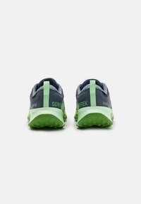 GORE-TEX hardloopschoenen met een donkerblauwe bovenkant, groene accenten en een getextureerde groene zool. Heeft een gevoerde kraag en hiel-lussen.