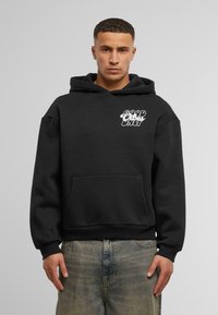 Felpa nera in cotone con tasca a marsupio. Presenta una grafica "GOOD VIBES ONLY" in bianco sul petto. Vestibilità comoda, polsini e orlo a coste.
