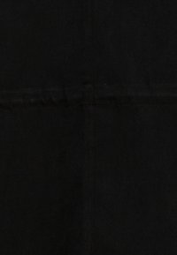 Tessuto nero con una superficie liscia, caratterizzato da un design semplice e taglio dritto. Dettagli delle cuciture presenti lungo il centro.