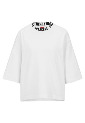 Camiseta de algodón blanca con un corte ancho y holgado y mangas cortas. Presenta una banda de logo en blanco y negro alrededor del cuello.