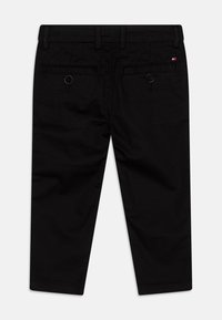 Pantaloni neri a gamba dritta con passanti per cintura, due tasche posteriori con bottone e un piccolo logo rettangolare rosso, bianco e blu sulla tasca destra.