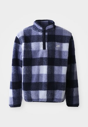 Pullu en polaire Nike bleu marine et à carreaux bleu clair. Doté d'une demi-fermeture éclair et d'un tissu doux et texturé. Petit logo sur la poitrine.
