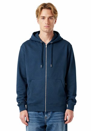 Sweat à capuche zippé bleu marine en tissu mélangé coton, avec une poche avant, un cordon de serrage pour la capuche, et des poignets côtelés. Texture douce visible.