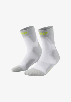 Chaussettes de sport en blanc et gris clair, avec un design en tricot texturé, un bout renforcé et des détails en logo vert fluo près de la cheville.