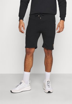Schwarze Sportshorts aus Baumwollmischung mit elastischem Bund und Kordelzug sowie seitlichen Taschen. Goldenes Logo-Accessoire am Bein.