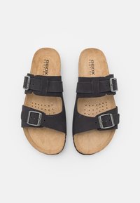 Sandali neri slip-on con una soletta in sughero, caratterizzati da due cinghie regolabili con fibbie e dettagli perforati sulla soletta interna. Visibile il marchio Geox.