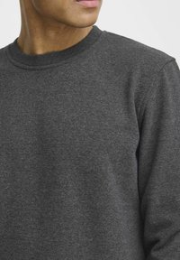 Donkergrijze crewneck sweatshirt gemaakt van zachte stof, met ribgebreide manchetten en kraag. Soepele textuur met minimale stikseldetails.