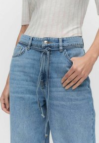 Vaaleansiniset farkut, joissa on rento istuvuus, vetoketjullinen vyötärö ja viisi taskua. Kangas näyttää hieman haalistuneelta ja siinä on pehmeä tekstuuri.