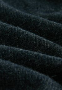 Dark wool fabric in folds, featuring a fine texture with visible fibers. The material appears soft and untextured with a deep black color.
