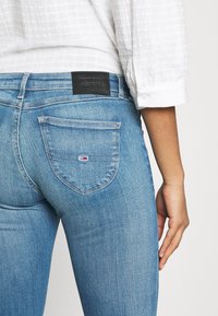 Slim-fit blå denimjeans med en blekt finish. Bakfickorna har böjd sömnad. Svart läderetikett på midjan.