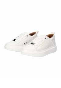 Baskets blanches en matériau synthétique lisse avec un bout arrondi, une semelle plate, un devant à lacets et un logo discret sur le côté.