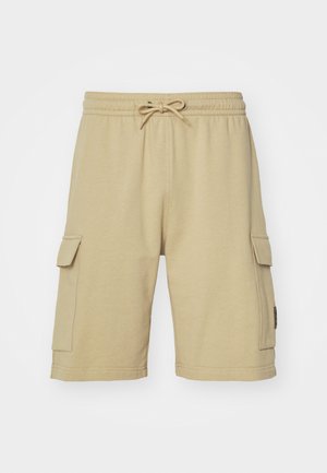 Beige cotton cargo shorts with an elastic waistband, drawstring, and side pockets. Smooth texture and knee-length design.