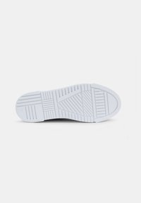 Fehér sneaker talp texturált gumival a tapadásért, hangsúlyos járásmintákkal és formázott vonalakkal a rugalmasság és a támogatás érdekében.