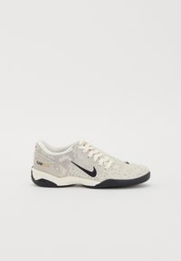Zapatillas gris claro con un upper texturizado, que presenta un logo de swoosh negro, cordones color crema y una suela de goma oscura. Los acentos incluyen una etiqueta dorada "total90".