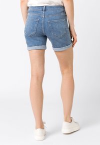 Jeansowe szorty w jasnoniebieskim kolorze, z podwiniętymi nogawkami, dwoma tylnymi kieszeniami i standardowym pasem. Gładka tekstura z lekkim przyblaknięciem.