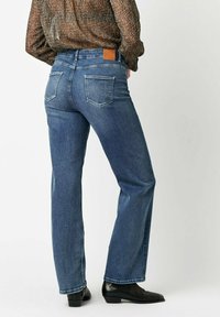 Blaue Denim-Jeans mit geradem Bein, ausgestattet mit zwei Gesäßtaschen, einem Lederpatch am Bund und einem leichten Farbverlauf.