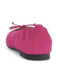 Roze suede balletflat met een afgeronde vorm, voorzien van een strik aan de voorkant, scalloped details op de hak en een zwarte zool.