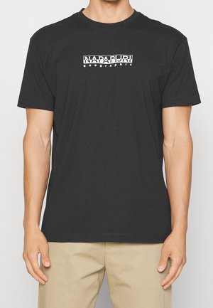 Black cotton t-shirt with short sleeves, crew neck, featuring a white "Napapijri" logo and "geographic" text in the center. Soft texture.