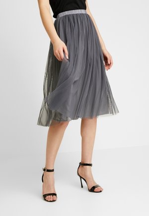 Falda midi de tul gris con un diseño texturizado y plisado. Presenta una cinturilla elástica y se combina con sandalias negras de tacón alto con tiras.