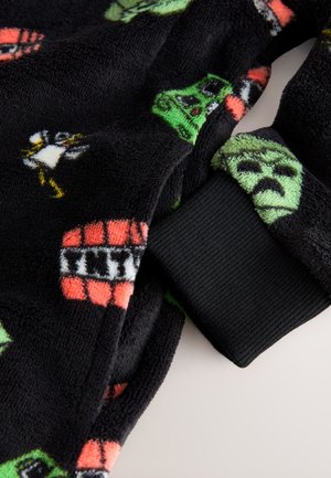 Tessuto in pile nero con vari motivi di personaggi dei cartoni animati colorati. Include un dettaglio di polsino a costine nero. Texture morbida.