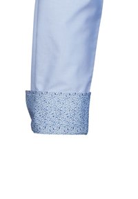 Polsino di camicia azzurro chiaro con motivo floreale in tonalità di blu. Tessuto liscio con un bordo decorato a contrasto sul bordo del polsino.