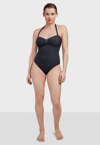 Bañador de una sola pieza negro y texturizado con cuello halter, detalle de fruncido en la parte frontal y un acento en forma de llave. Tejido suave y diseño ceñido.