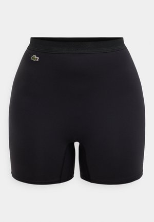 Pantalones cortos deportivos negros con textura suave, cintura elástica y un pequeño logo bordado en el lateral. Diseño ajustado con costuras mínimas.