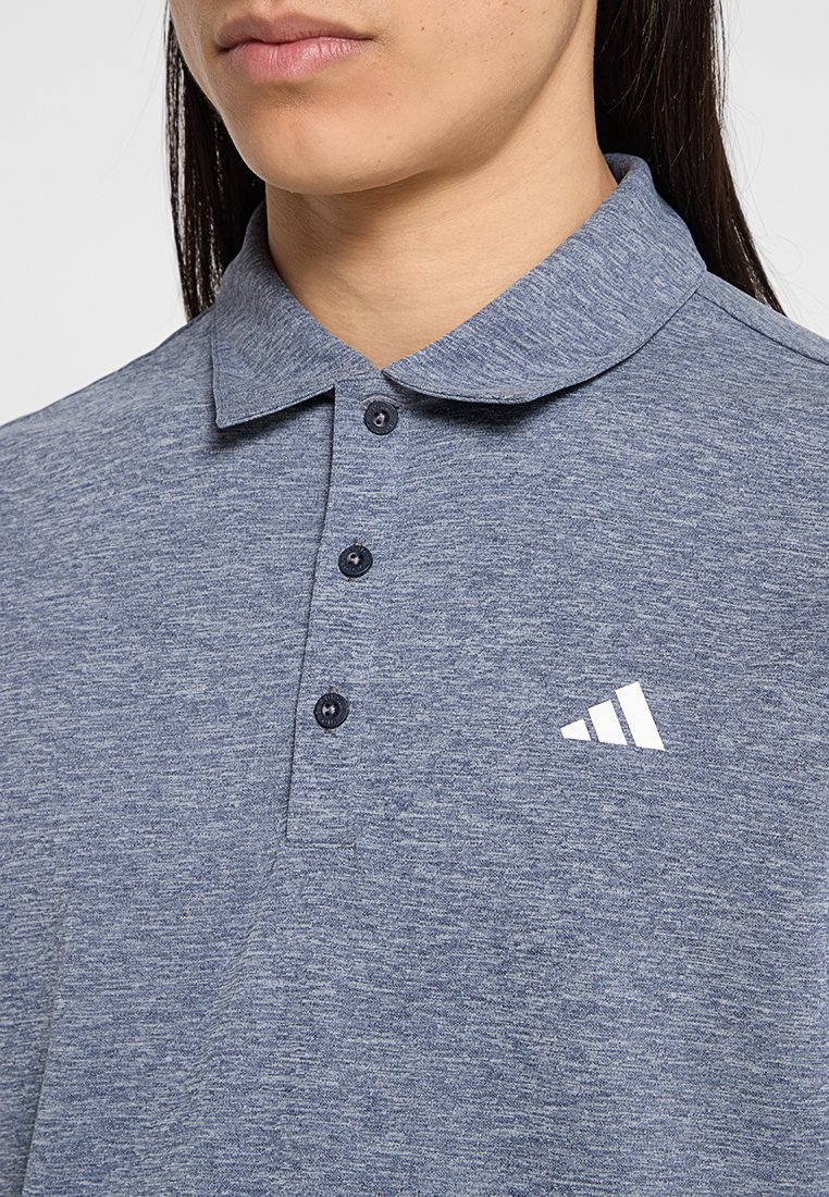 Camisa polo azul marino con tejido texturizado, tres botones y un logo de Adidas blanco en el pecho. Diseño de cuello corto.