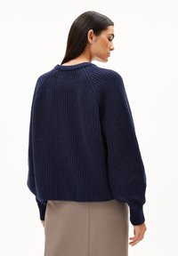 Donkerblauwe gebreide sweater met geribbelde structuur, oversized pasvorm en verlaagde schouders. Heeft een ronde halslijn en lange, iets gepofte mouwen.