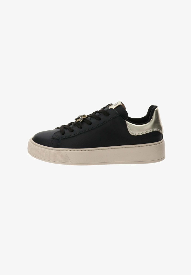 Sneaker in pelle nera con punta arrotondata, suola spessa beige, dettagli metallici argento sul tallone e allacciatura frontale con accessori decorativi.