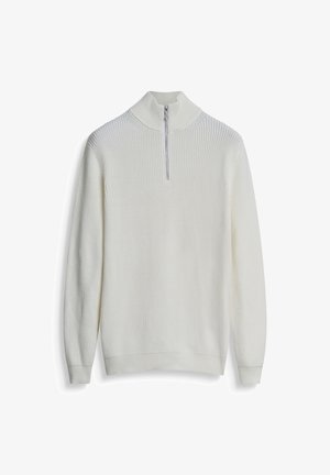 Witte trui met een hoge kraag, geribbelde textuur en lange mouwen. Voorzien van een halve rits bij de kraag en een aansluitende tailleband.
