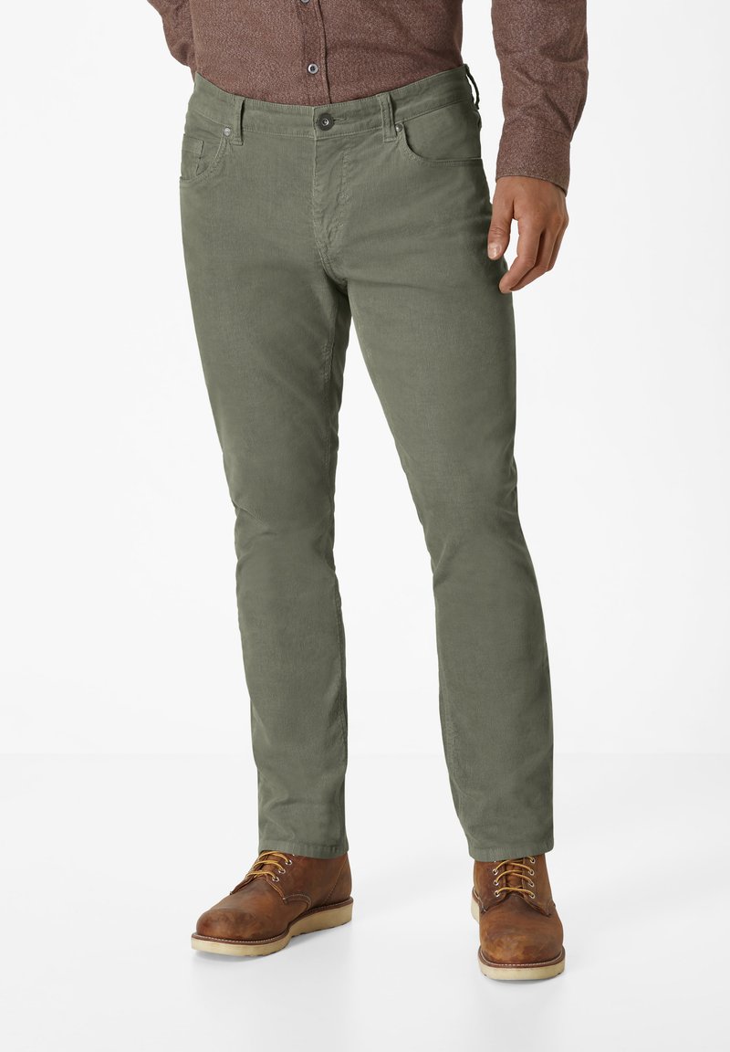 Olive green, slim-fit trousers with a smooth texture, five pockets, and a button closure, paired with brown lace-up boots.