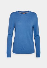 Pull bleu à manches longues en tissu doux, doté d'un col rond et de poignets et ourlets côtelés, avec des fentes latérales pour faciliter les mouvements.