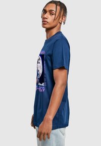 Mørkeblå bomulls t-skjorte med rund hals, korte ermer og grafisk trykk som viser en rapper og tekst i kontrasterende farger.