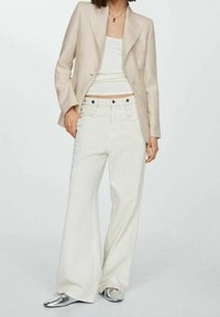Blazer beige, top corto bianco e pantaloni larghi bianchi. Scarpe basse in argento. Design minimalista con linee pulite e colori neutri. Texture del tessuto liscia.
