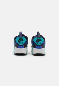 Černé a tyrkysové tenisky Nike Air mají texturovaný síťovaný svršek, polstrovaný límec a kontrastní gumovou podrážku s poutkem na patě.