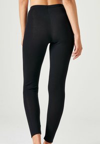 Zwarte legging gemaakt van rekbaar materiaal met een gladde textuur, met een hoge tailleband en een aansluitend ontwerp dat naar de enkels toe versmalt.