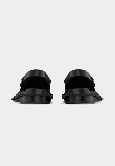 Paire de mocassins noirs en cuir à enfiler avec boucles, vue de dos sur un fond clair uni.