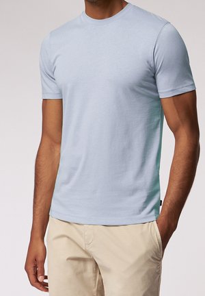 Light blue short-sleeve t-shirt made of soft fabric, featuring a classic crew neck and a smooth texture, paired with beige pants.