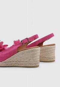 Chaussures à semelle compensée rose avec accents floraux, tige en tissu, talon compensé en jute naturel et bride réglable avec boucle.